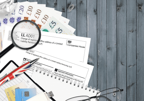 How to change address on Companies House, AD01 form with UK banknotes, pen, and magnifying glass on a desk